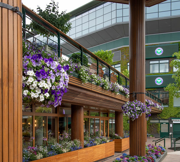 Courtside Brasserie at Wimbledon, a stylish restaurant with lush floral decor, wooden architecture, and a prime view of the iconic venue