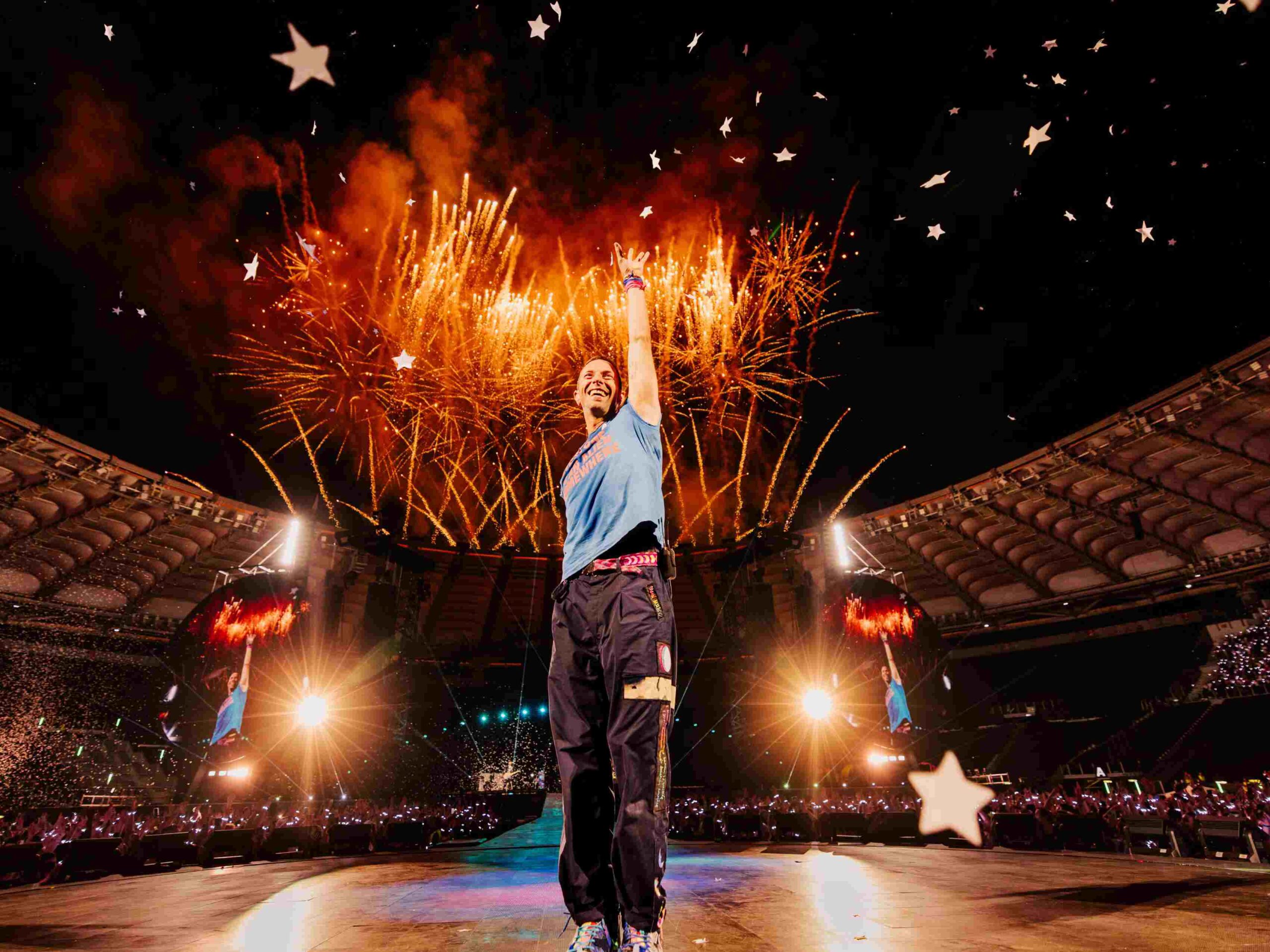 Chris Martin of Coldplay performs live with fireworks and confetti at a packed stadium during the Music of the Spheres World Tour