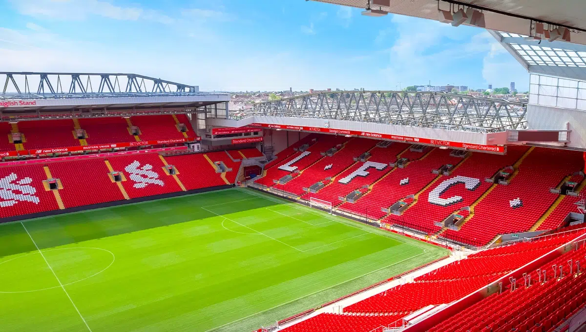 Modern render of Liverpool FC stadium with red seating, L.F.C. initials, and a bright, open sky above the pitch