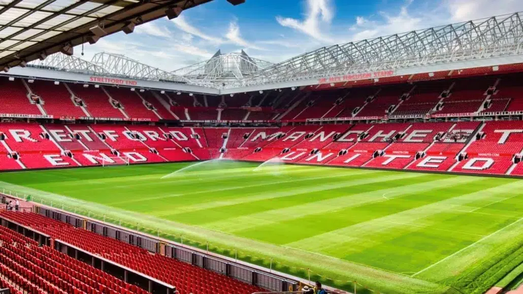 View of Old Trafford Stadium, home of Manchester United, featuring the iconic Sir Alex Ferguson Stand and the red seating spelling out “MANCHESTER UNITED.”