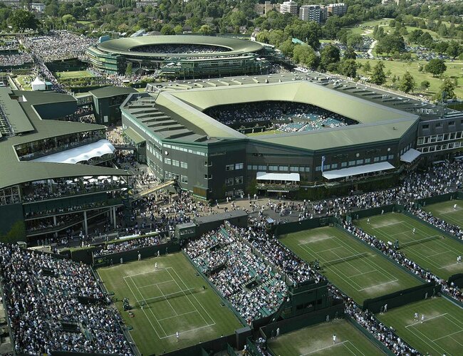 Aerial view of Wimbledon Centre Court and surrounding tennis courts, packed with spectators, showcasing the iconic venue's grand scale