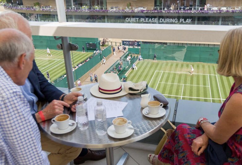 Guests enjoying coffee at Wimbledon’s The Rooftop, overlooking the tennis courts with a premium view of live matches