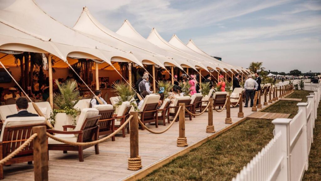 Royal Ascot The Veranda – A luxurious open-air hospitality area featuring elegant white tents, plush seating, and stylish guests enjoying premium race day experiences in a relaxed and sophisticated setting