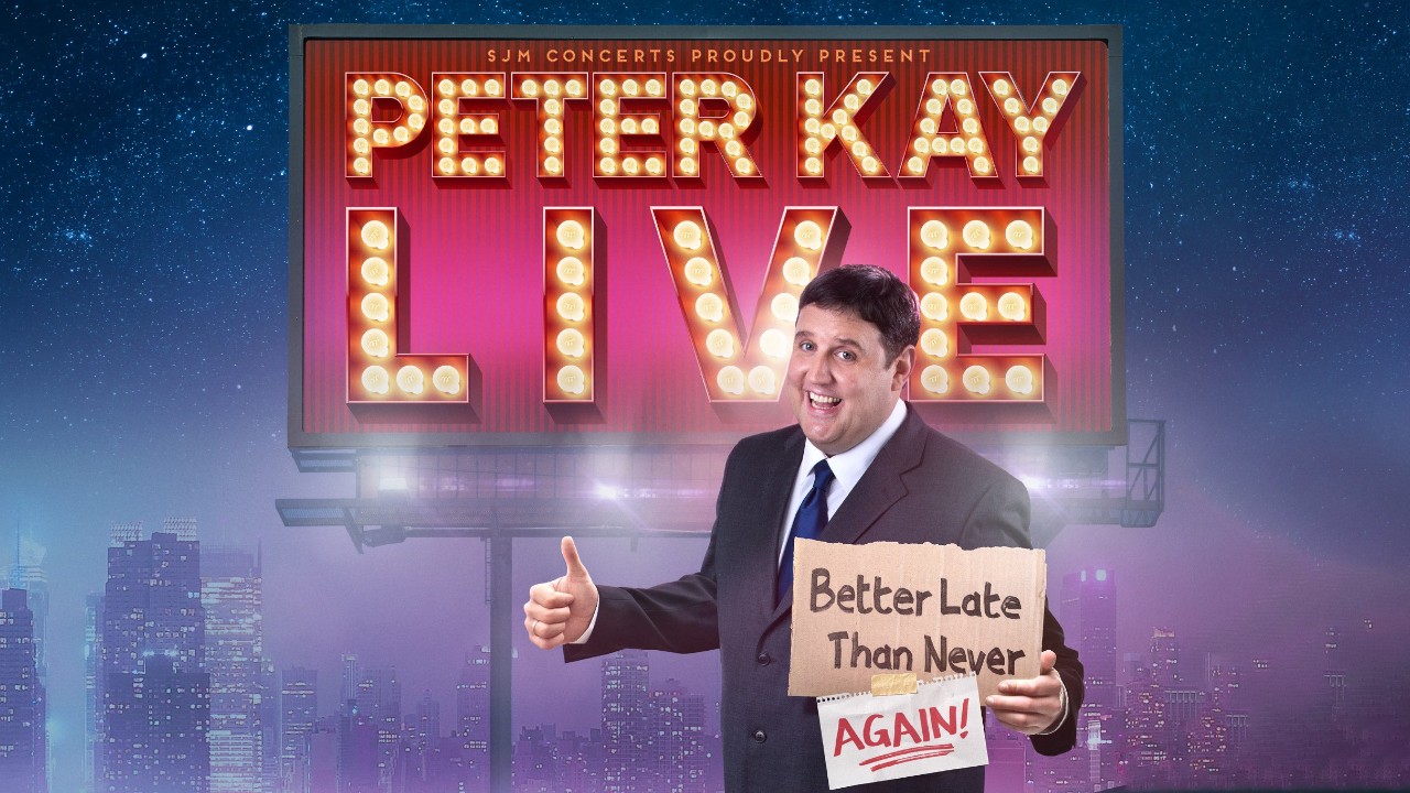 Poster for Peter Kay Live, showing comedian Peter Kay in a suit, smiling and giving a thumbs-up. He holds a cardboard sign that reads “Better Late Than Never... AGAIN!” in front of a giant lit-up billboard. The backdrop features a city skyline under a starry night sky, evoking the return of his much-anticipated comedy tour