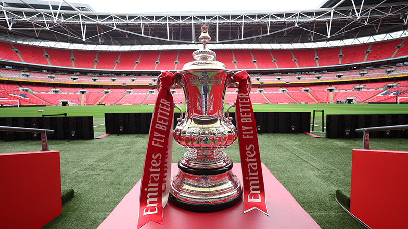 The Emirates FA Cup trophy on display at Wembley Stadium, set for the semi-final match with iconic red seats in the background