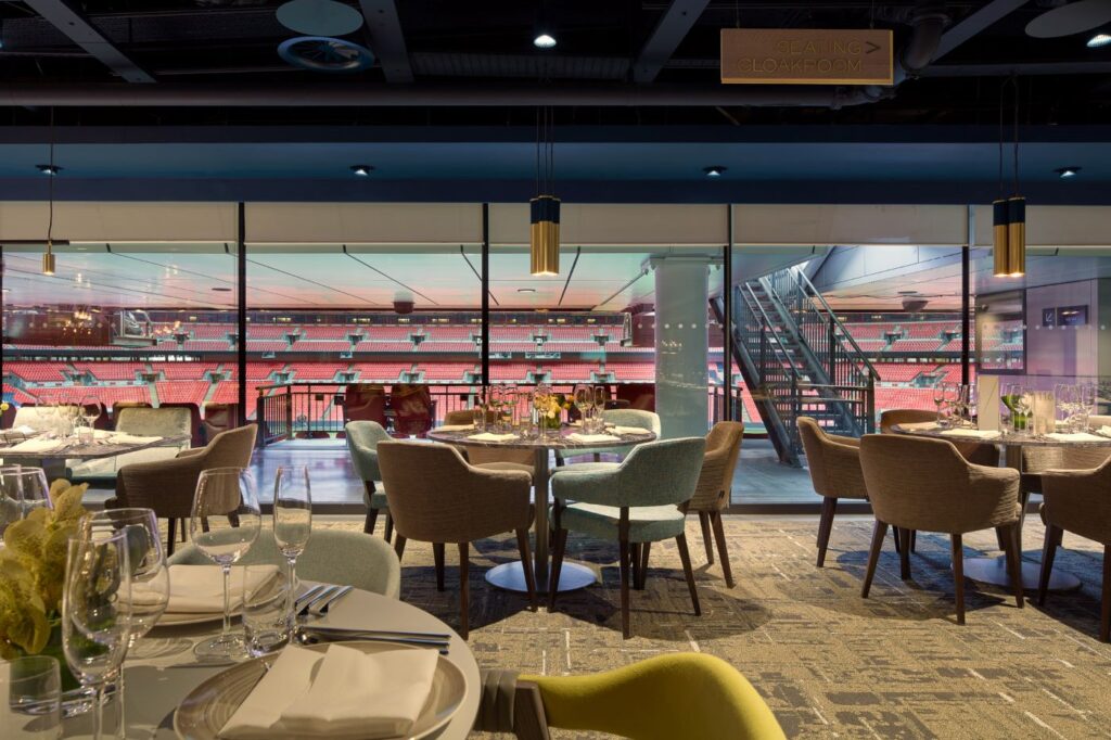 Wembley Stadium hospitality suite featuring elegant dining tables, luxurious seating, and panoramic views of the pitch through floor-to-ceiling windows.
