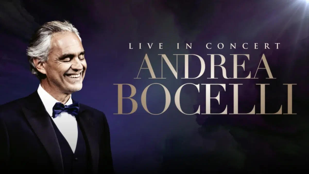 Promotional image for Andrea Bocelli Live in Concert featuring the tenor in a tuxedo, smiling with eyes closed, set against a dark, elegant background with softly glowing light