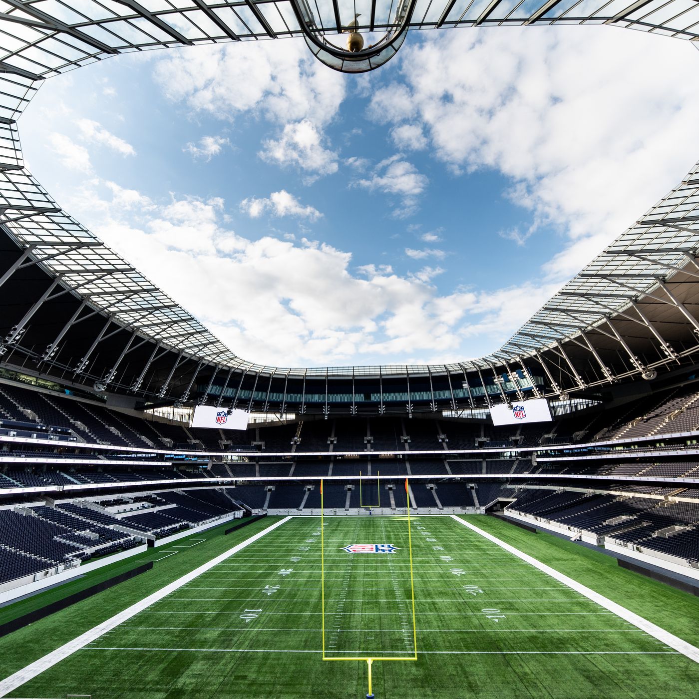 NFL field setup at Tottenham Hotspur Stadium, featuring goalposts, yard markings, and the NFL logo at midfield under a clear sky.