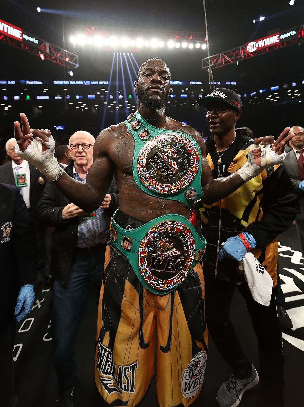 Deontay wilder in the ring with boxing belts on after a victory